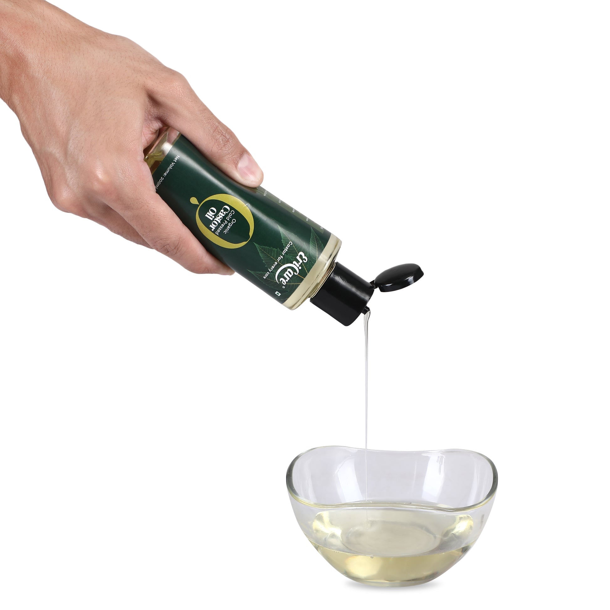 Hand pouring transparent, yellow organic castor oil, demonstrating its high quality and hexane-free nature. The oil emits a mild aroma, showcasing its purity and organic origin.